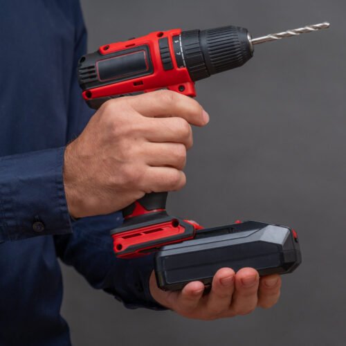 A man installs a battery in a cordless screwdriver. a man installs a battery in a screwdriver. close-up on a gray background. copy space