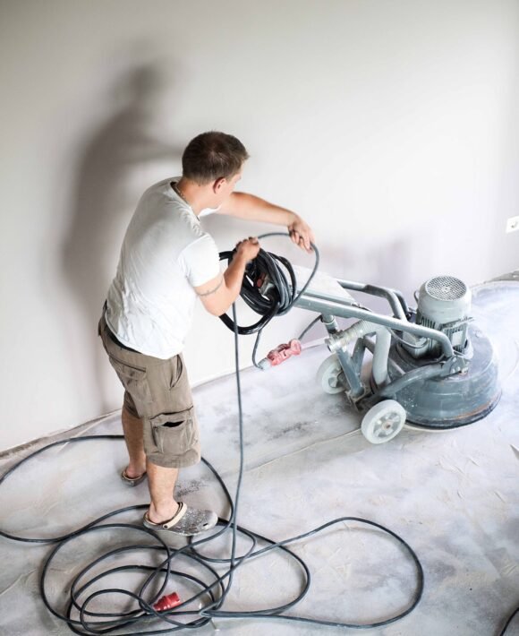 construction-2025-03-10-05-13-10-utc Construction worker in a family home living room that grind the concrete surface before applying epoxy flooring.Polyurethane and epoxy flooring.Concrete grinding.