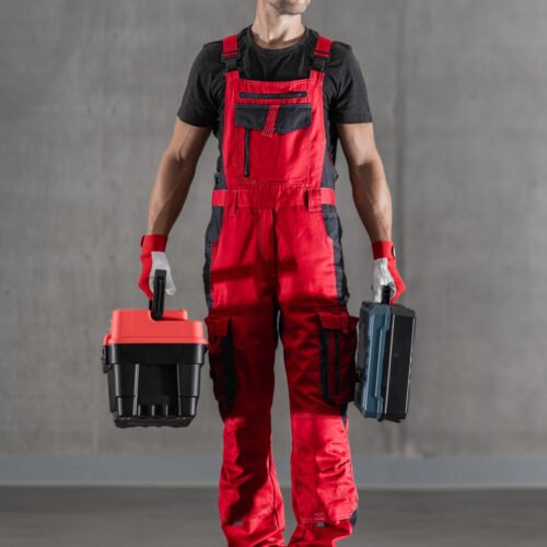 Professional Fixer Arrived at the Job Site Mobile Home Repair Worker with Toolboxes in His Hands Just Arrived at the Client’s Location. Handyman Door-to-Door Services. Solid Grey Background. Horizontal Photo.